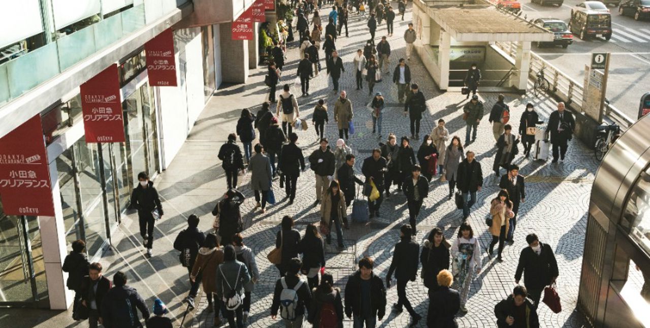 Sunny city with lots of people walking in different directions.